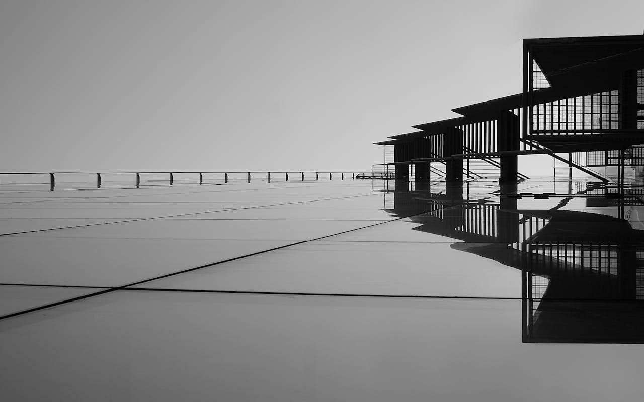 heros-img A striking minimalist black and white image featuring architectural reflections on glass surfaces.